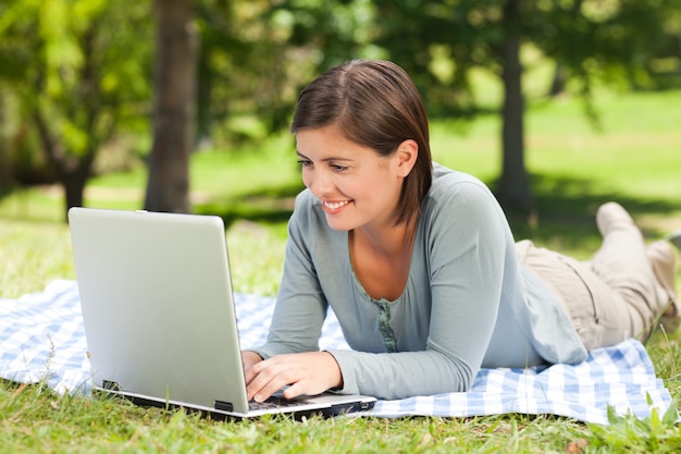 Frau, die an ihrem Laptop im Park arbeitet