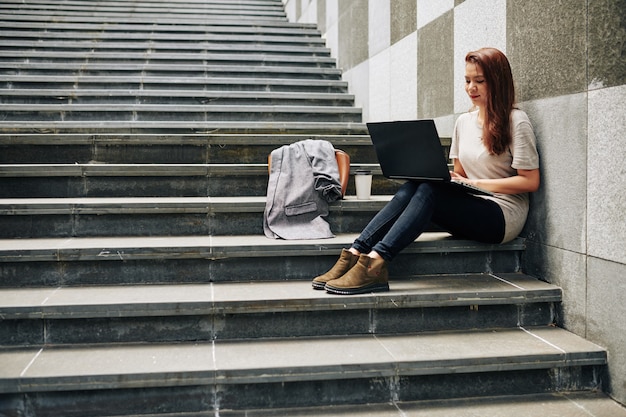 Frau, die Artikel auf Laptop schreibt