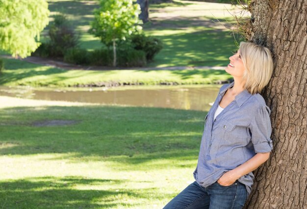 Frau, die auf Baumstamm im Park sich lehnt