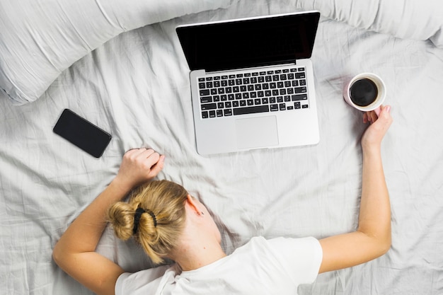 Foto frau, die auf bett mit laptop schläft