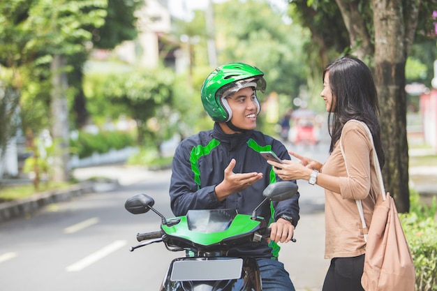 Frau, die auf Bürgersteig steht, der ein kommerzielles Motorradtaxi bestellt