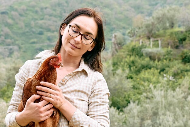 Frau, die auf dem Bauernhof braune Henne in den Händen hält Freegrazing Haushenne auf einem traditionellen Bio-Bauernhof mit Freilandgeflügel
