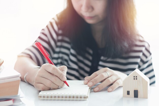 Frau, die auf dem Papier schreibt und zu Hause für Geschäft, Selbstquarantäne, zu Hause bleiben und soziale Distanzierung arbeitet