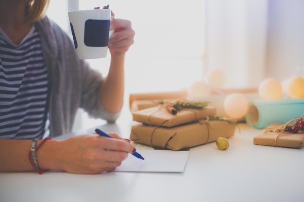 Frau, die auf dem Schreibtisch mit Weihnachtsgeschenkbox sitzt Hände der Frau