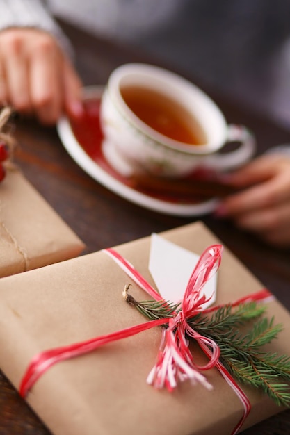 Frau, die auf dem Schreibtisch mit Weihnachtsgeschenkbox sitzt Hände der Frau