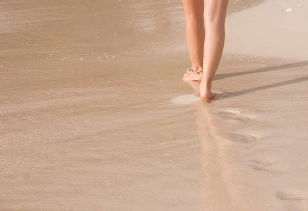 Frau, die auf dem Strand geht und Schritte verlässt