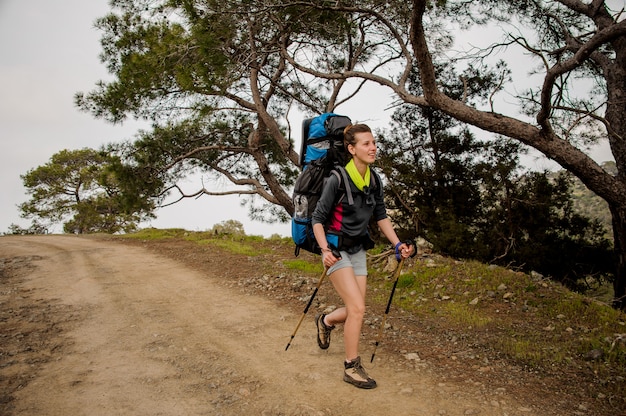 Frau, die auf den Weg mit dem Wandern des Rucksacks geht