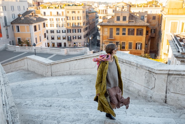 Frau, die auf der berühmten spanischen Treppe im Hintergrund der Altstadt von Rom läuft