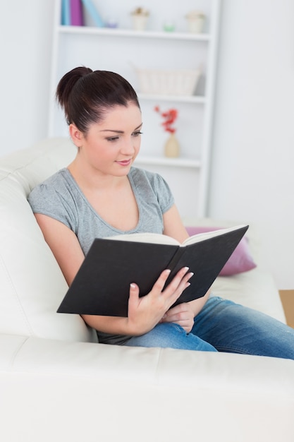 Frau, die auf der Couch sitzt und ein Buch liest