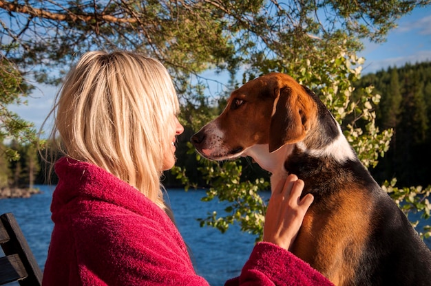 Frau, die auf einen Hund gegen den See schaut