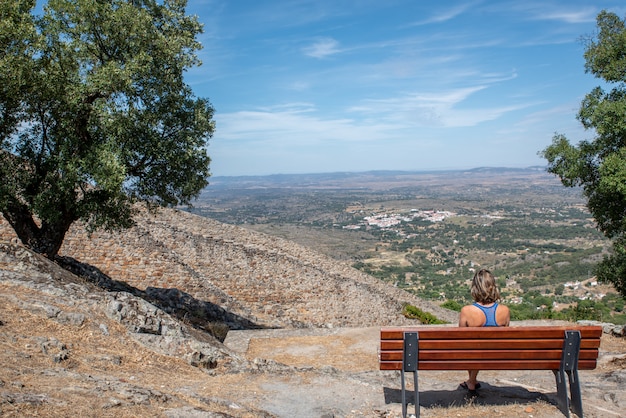 Frau, die auf einer Bank sitzt, die die Landschaft genießt