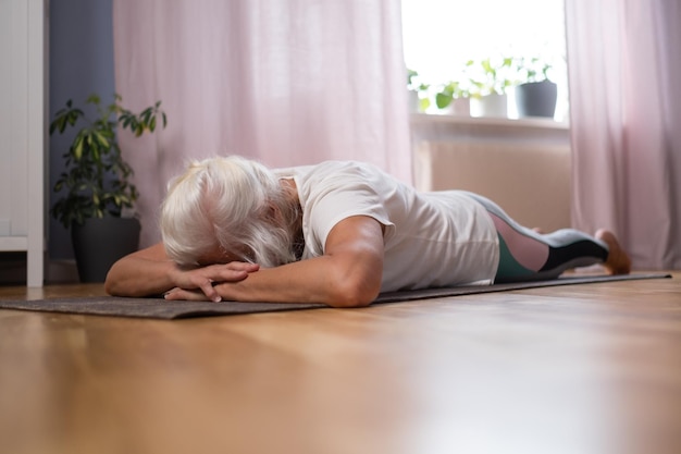 Frau, die auf einer Yogamatte liegt und sich entspannt, während sie zu Hause Yoga genießt