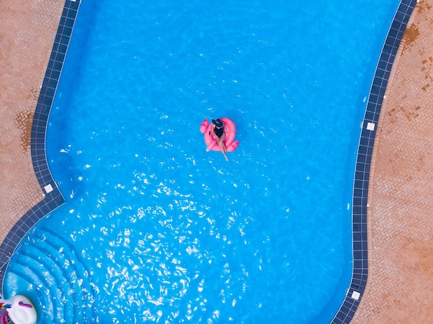 Frau, die auf Flamingo-Pool schwimmt, schwimmen in einem großen luxuriösen Pool, Drohnen-Luftbild