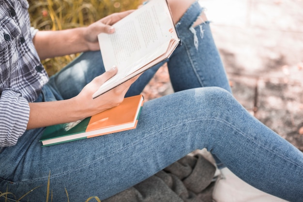 Frau, die auf Gras mit Buch in den Händen sitzt