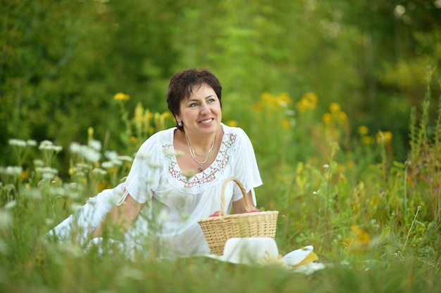 Frau, die auf Gras mit Weidenkorb sitzt