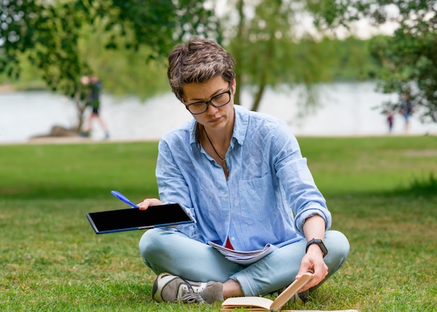 Frau, die auf grünem Gras sitzt und studiert