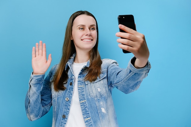 Frau, die auf Handy schaut, macht Videoanruf