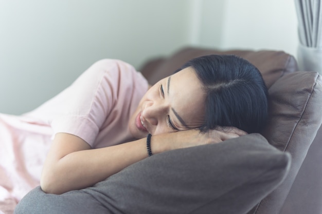 Frau, die auf Sofa im Wohnzimmer liegt.