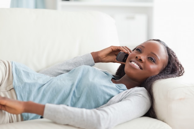 Frau, die auf Sofa mit Telefon liegt