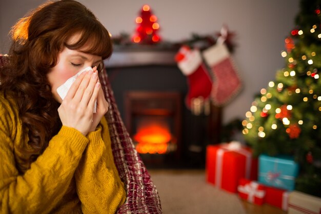 Frau, die auf Sofa sitzt und ihre Nase am Weihnachten durchbrennt