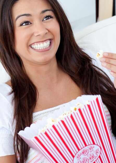 Frau, die auf Sofa sitzt und Popcorn isst