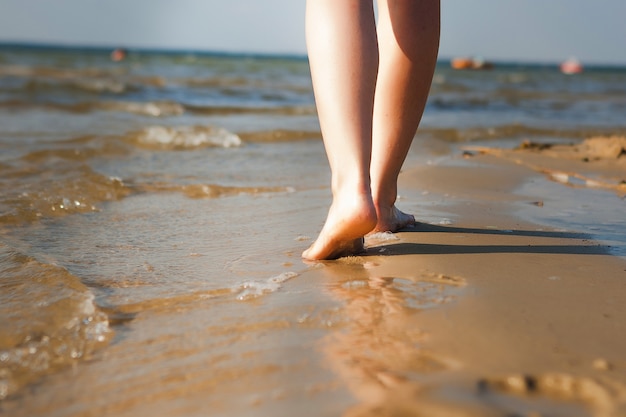 Frau, die auf Strand geht und Fußspuren im Sand hinterlässt