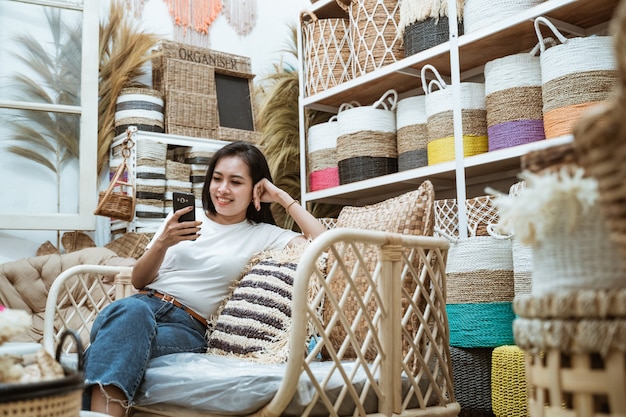 Frau, die beiläufig auf dem Sofa unter Verwendung eines Smartphones in der Handwerksgalerie sitzt