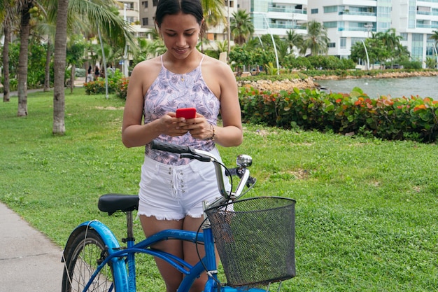 Frau, die beim Ausruhen auf einer Fahrradtour in der Stadt das Telefon überprüft