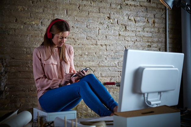 Frau, die bewegliche Musikkopfhörer im Büro hört