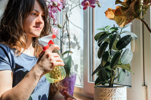 Frau, die Blumen in ihrem Haus wässert