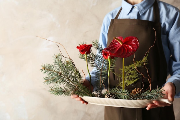 Frau, die Blumenkomposition auf farbigem Hintergrund hält