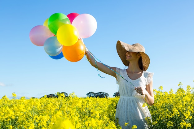 Frau, die bunte Luftballons im Senffeld hält