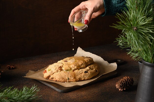 Frau, die Butter auf Weihnachtsstollen gießt