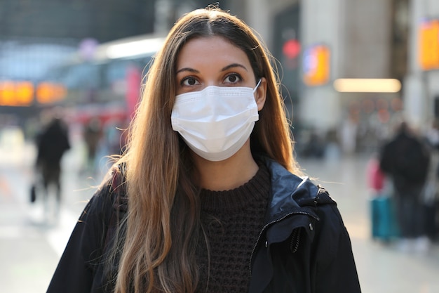 Frau, die chirurgische Maske am Bahnhof trägt