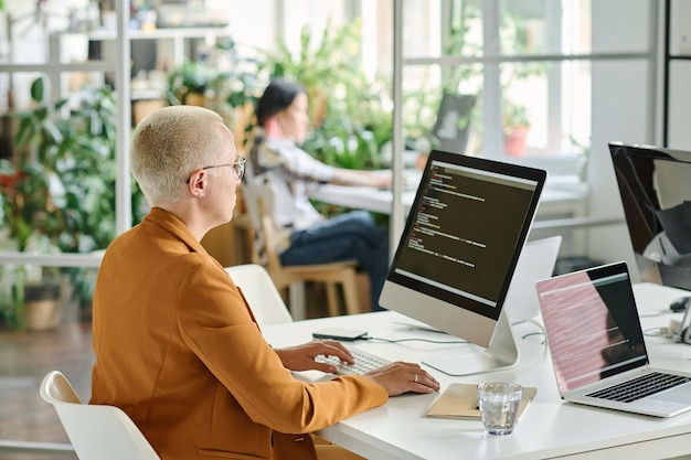 Foto frau, die codes auf dem computer im büro eingibt