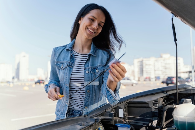 Frau, die das Öl ihres Autos prüft