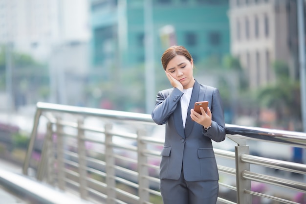 Frau, die das Smartphone tippt und sie fühlt sich traurig