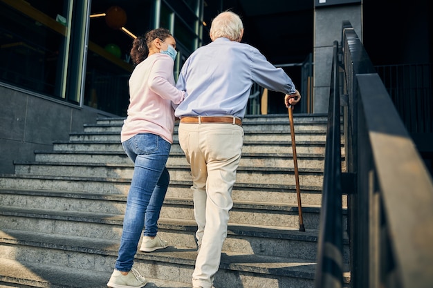 Frau, die dem älteren Mann beim Treppensteigen hilft