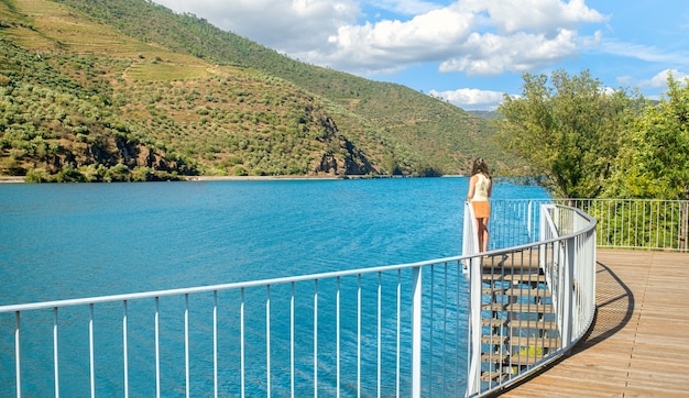 Frau, die den Fluss und die Berge von einer Terrasse bewundert