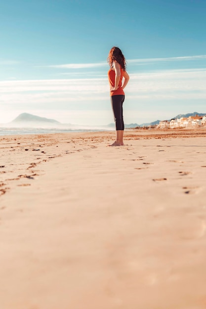 Frau, die den Horizont auf dem Sand des Strandes beobachtet