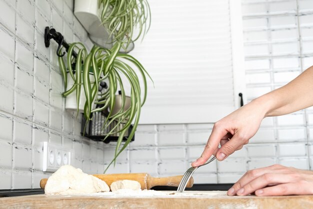 Frau, die den Teig mit einer Gabel für blindes Backen durchbohrt