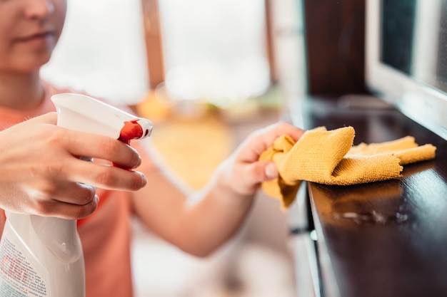 Frau, die den Tisch mit Mikrofasertuch abwischt Detailansicht Housekeeping-Konzept