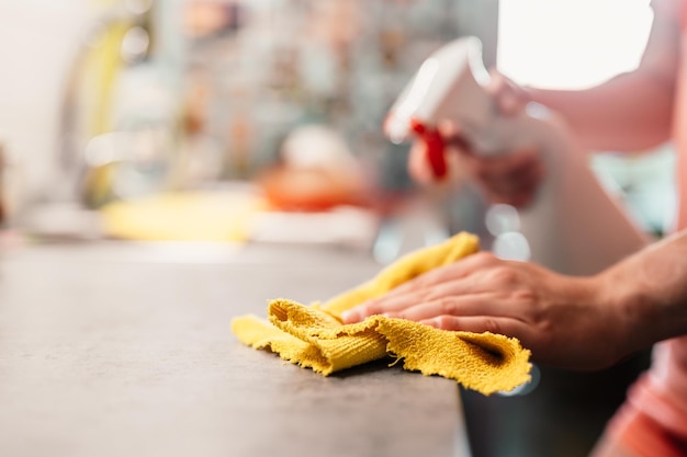 Frau, die den Tisch mit Mikrofasertuch abwischt Detailansicht Housekeeping-Konzept