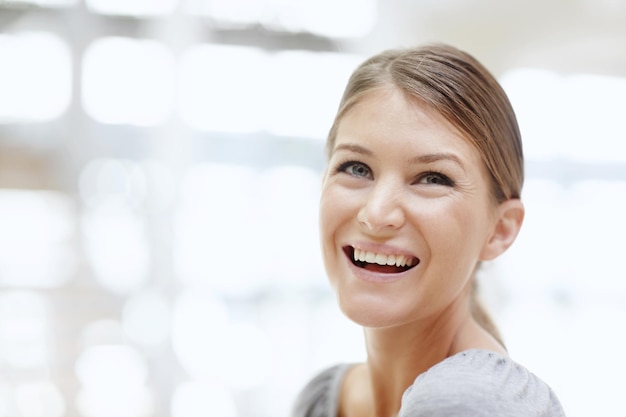 Frau, die denkt und lächelt für eine positive Einstellung, Frieden und Entwicklung mit einem nachdenklichen freien Verstand, weibliche Person, die Planung und Vision im Büro für perspektivische Reflexion oder Erinnerung mit Licht oder Idee.