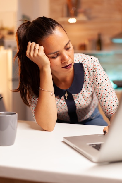 Frau, die die Augen wegen Erschöpfung geschlossen hält, während sie spät in der Nacht an einem Projekt für die Arbeit arbeitet. Mitarbeiter, die um Mitternacht moderne Technologie verwenden, machen Überstunden für Job, Geschäft, beschäftigt, Karriere, Netzwerk.