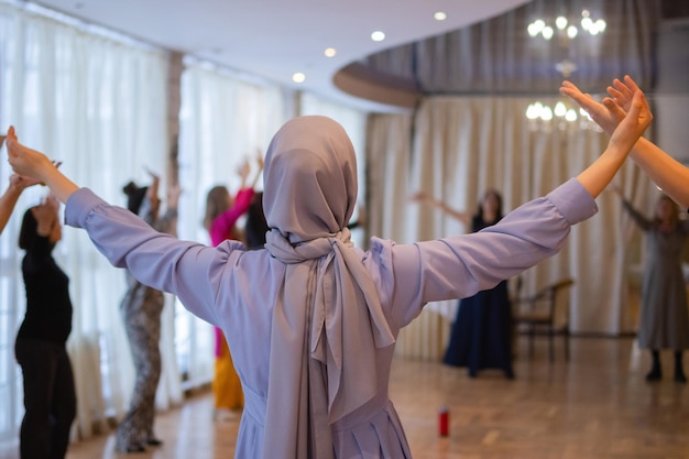 Frau, die die Hände hochlegt und tanzt Aufgeregte junge Frau, die einen Sieg feiert Muslimische Frau in traditioneller islamischer Kleidung hijab Geburtstag Neujahrsfeier Konzept