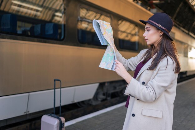 Frau, die die Karte auf dem Bahnhof betrachtet.