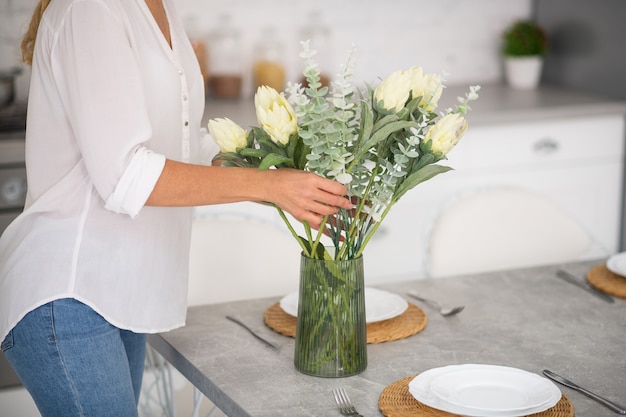 Frau, die die Küche mit weißen schönen Blumen verziert
