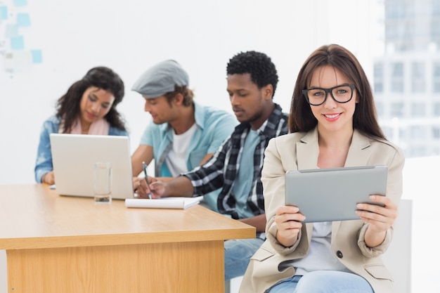 Frau, die digitale Tablette mit Kollegen hinten im Büro verwendet