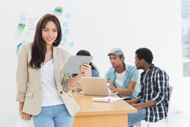 Frau, die digitale Tablette mit Kollegen hinten im Büro verwendet